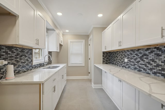 kitchen with backsplash, light stone counters, sink, and white cabinets