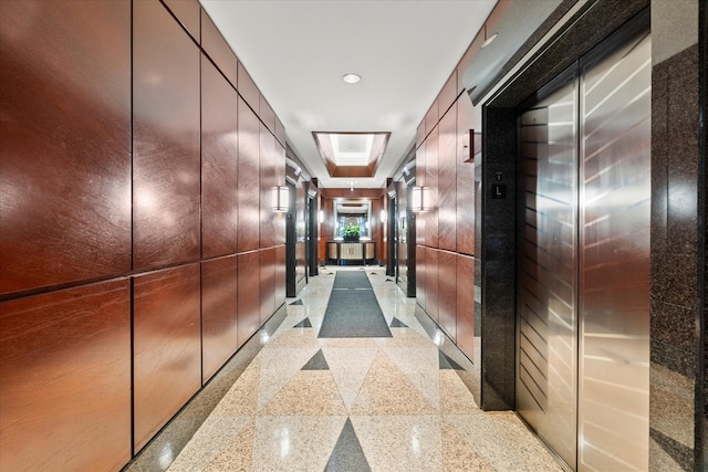 hallway featuring wooden walls and elevator