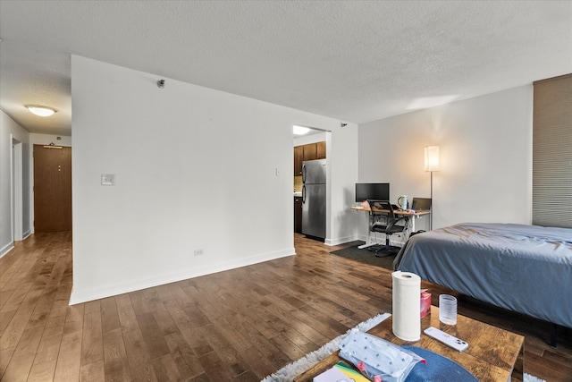 bedroom featuring a textured ceiling, stainless steel refrigerator, and dark wood-type flooring