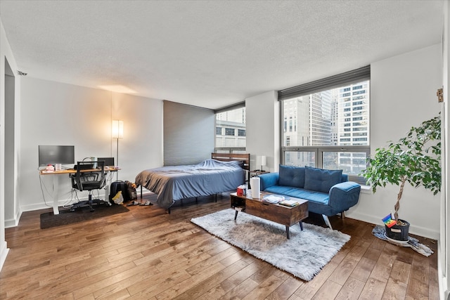 bedroom with multiple windows, wood-type flooring, and a textured ceiling