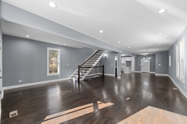 unfurnished living room featuring a chandelier and dark hardwood / wood-style floors