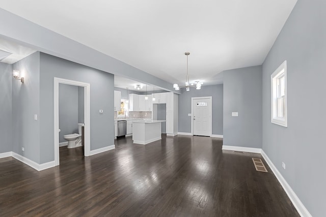 unfurnished living room with a notable chandelier and dark wood-type flooring