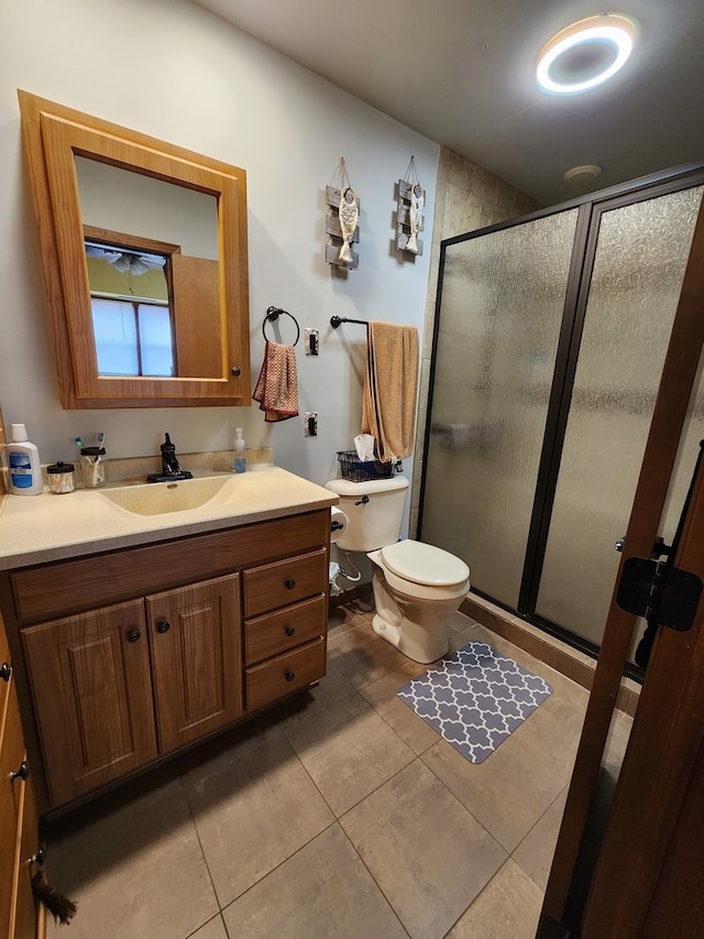 bathroom with tile patterned flooring, vanity, toilet, and a shower with shower door