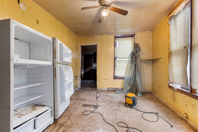 interior space with white refrigerator, multiple windows, and ceiling fan