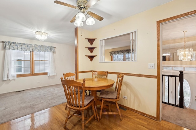 dining area featuring hardwood / wood-style flooring and ceiling fan with notable chandelier