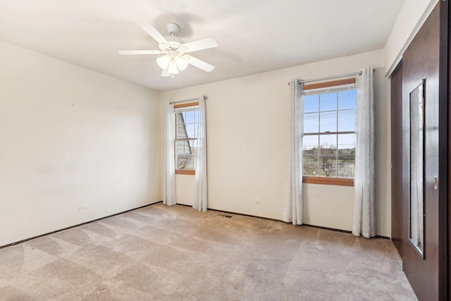 carpeted spare room with ceiling fan and plenty of natural light