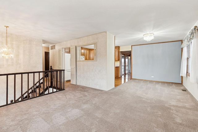 carpeted empty room with a notable chandelier