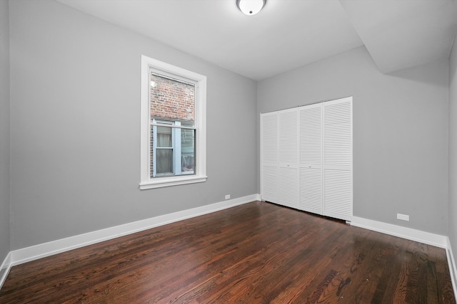 unfurnished bedroom with dark wood-type flooring and a closet