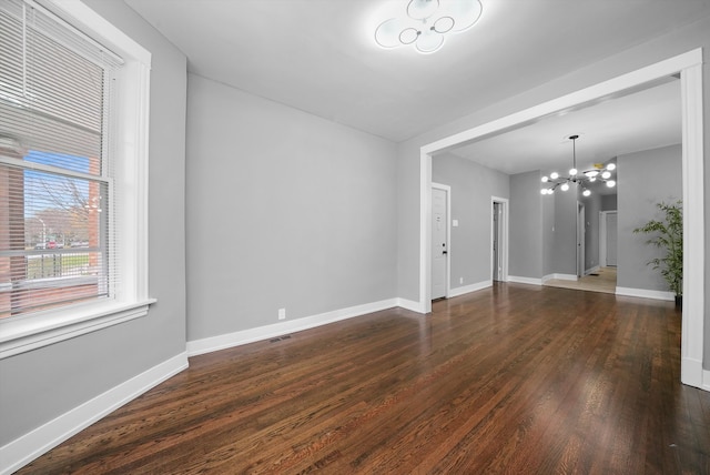 empty room featuring dark hardwood / wood-style flooring and a notable chandelier