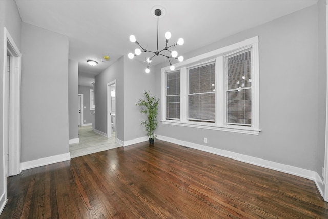 unfurnished dining area featuring dark wood-type flooring and an inviting chandelier