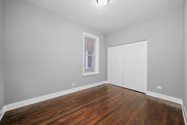 unfurnished bedroom featuring dark wood-type flooring and a closet