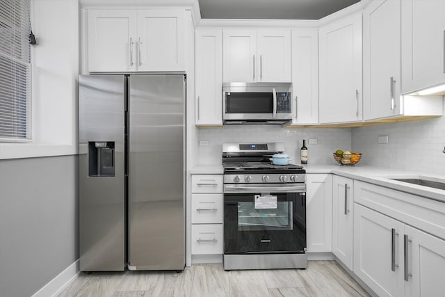 kitchen with backsplash, sink, white cabinetry, and stainless steel appliances