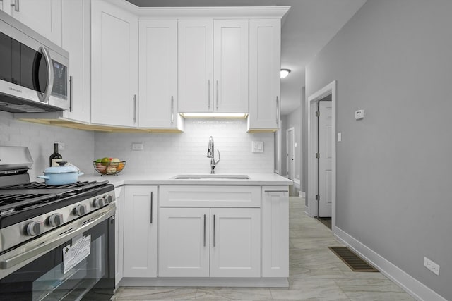 kitchen with white cabinets, decorative backsplash, sink, and stainless steel appliances