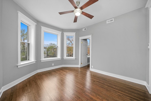 unfurnished room with ceiling fan, dark wood-type flooring, and a healthy amount of sunlight