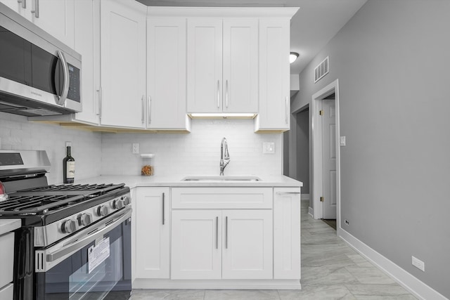 kitchen with tasteful backsplash, white cabinetry, sink, and appliances with stainless steel finishes