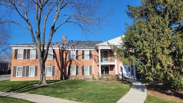 view of front of property featuring a balcony and a front lawn