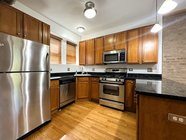 kitchen featuring decorative light fixtures, sink, light wood-type flooring, and stainless steel appliances