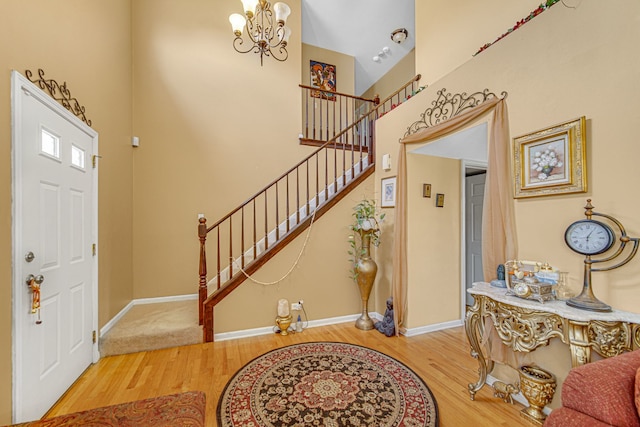 entrance foyer with a towering ceiling, wood-type flooring, and a notable chandelier