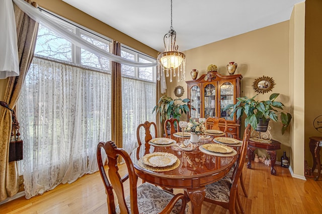 dining space with an inviting chandelier and light hardwood / wood-style flooring