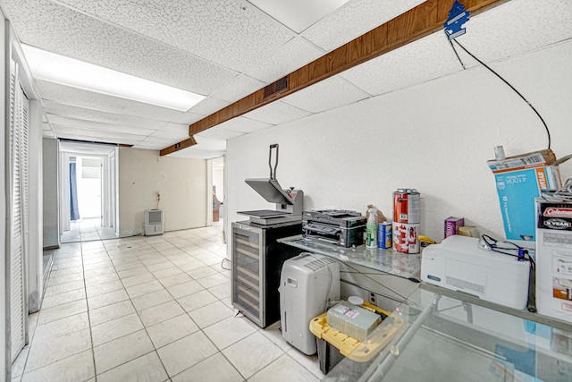 kitchen with a drop ceiling, beverage cooler, and light tile patterned flooring