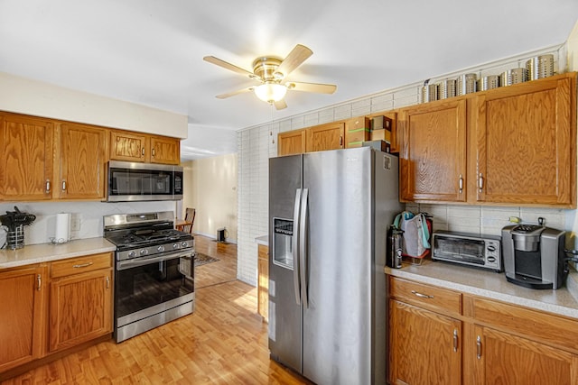 kitchen featuring decorative backsplash, ceiling fan, light wood-type flooring, and appliances with stainless steel finishes