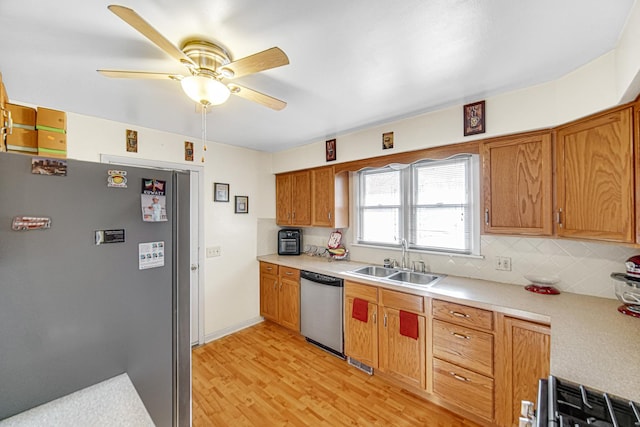 kitchen with backsplash, sink, ceiling fan, appliances with stainless steel finishes, and light hardwood / wood-style floors