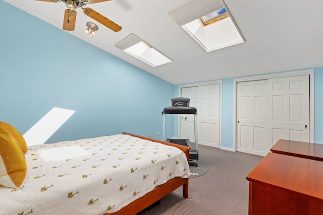 bedroom with carpet flooring, two closets, ceiling fan, and vaulted ceiling with skylight