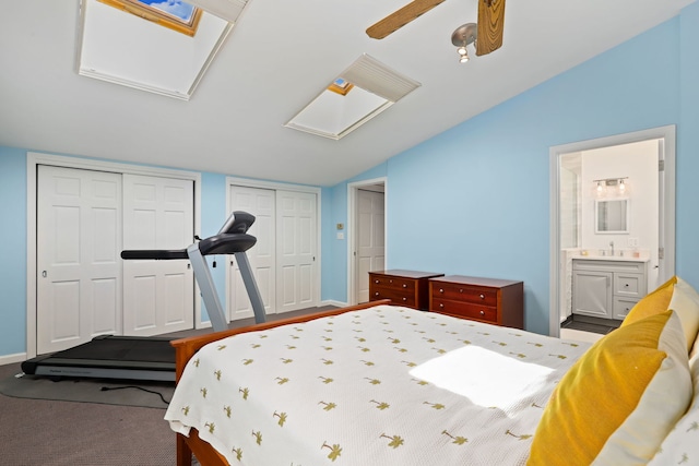 carpeted bedroom with two closets, sink, ensuite bath, vaulted ceiling, and ceiling fan