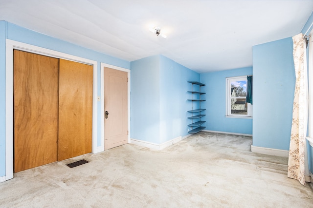 unfurnished bedroom featuring light carpet and a closet