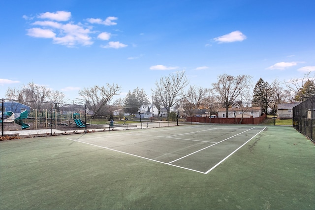 view of tennis court featuring a playground