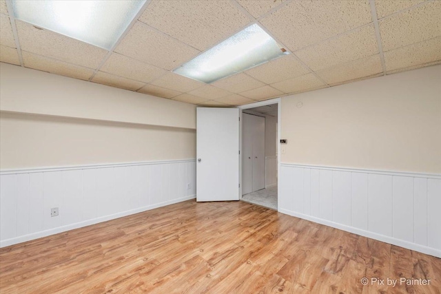 basement with light hardwood / wood-style floors and a drop ceiling