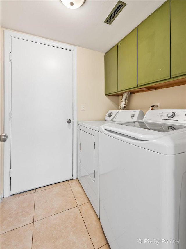 laundry area with light tile patterned floors, washing machine and dryer, and cabinets