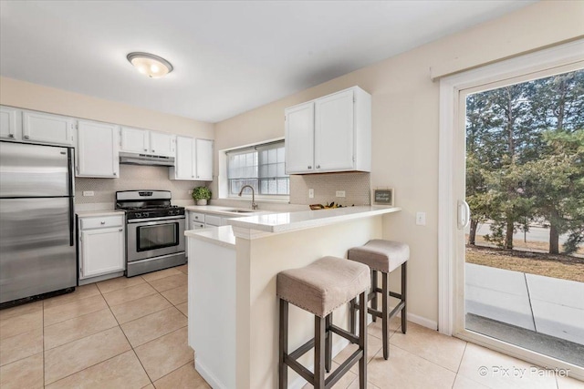 kitchen featuring a kitchen bar, kitchen peninsula, white cabinets, and appliances with stainless steel finishes