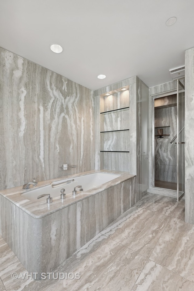 bathroom featuring a relaxing tiled tub and tile walls