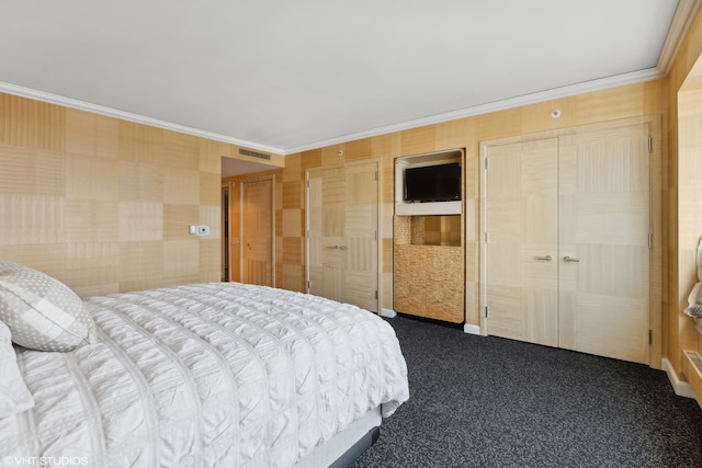 bedroom featuring wood walls, carpet floors, ornamental molding, and two closets