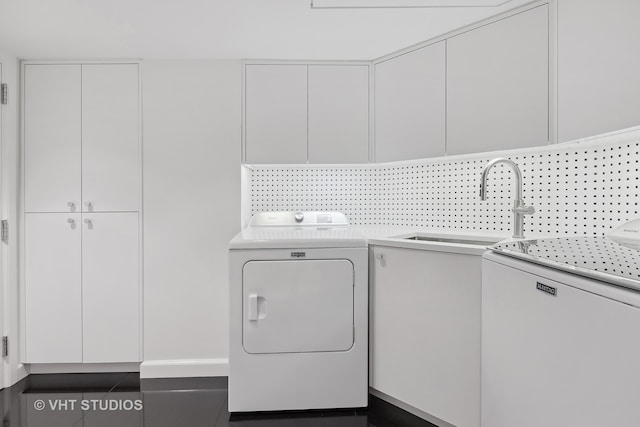 washroom with washer and dryer, dark tile patterned floors, cabinets, and sink