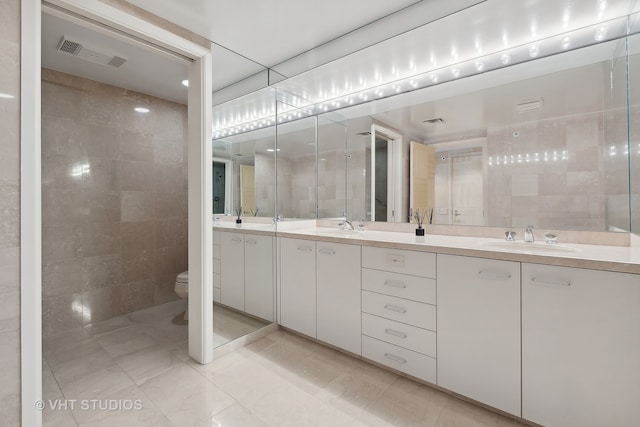 bathroom with tile patterned flooring, vanity, toilet, and tile walls