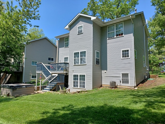 rear view of house with a lawn, central air condition unit, a wooden deck, and a hot tub