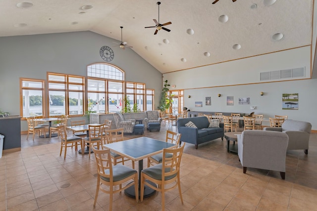 dining space featuring a textured ceiling, ceiling fan, high vaulted ceiling, and light tile patterned floors