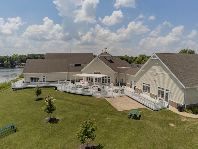 rear view of house with central air condition unit, a patio area, a lawn, and a water view