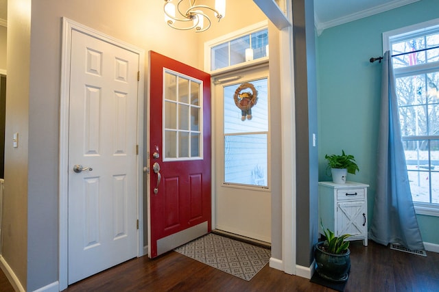 foyer entrance with a notable chandelier, crown molding, and dark wood-type flooring