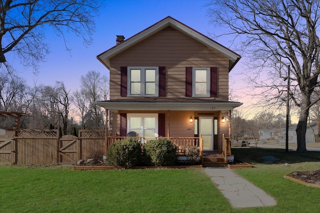 front of property featuring covered porch and a yard