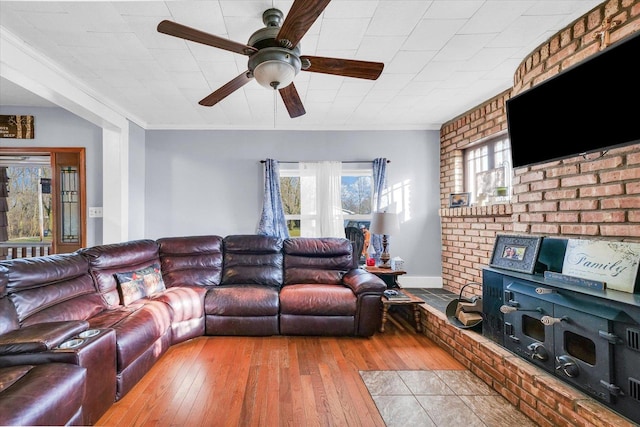 living room with ceiling fan, light hardwood / wood-style floors, ornamental molding, and brick wall