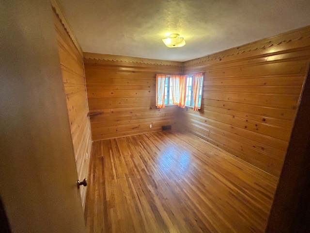 empty room with wood walls and wood-type flooring