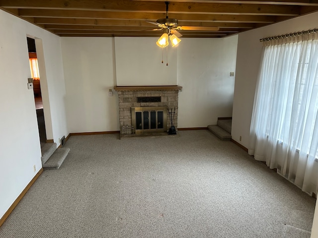 unfurnished living room featuring beamed ceiling, carpet, a fireplace, and a wealth of natural light