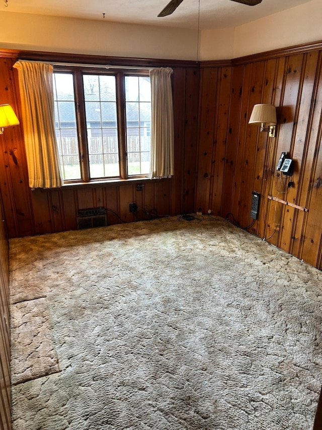 spare room featuring carpet floors, ceiling fan, and wooden walls