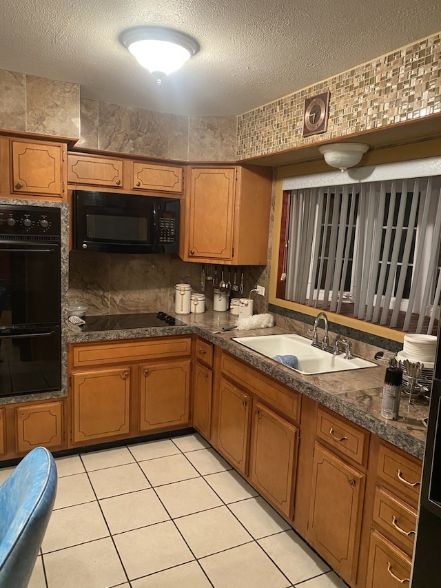 kitchen featuring sink, light tile patterned floors, black appliances, and a textured ceiling