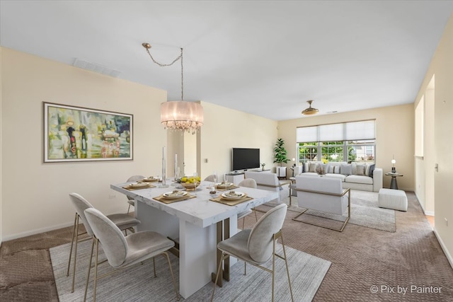 dining area with light colored carpet and a notable chandelier