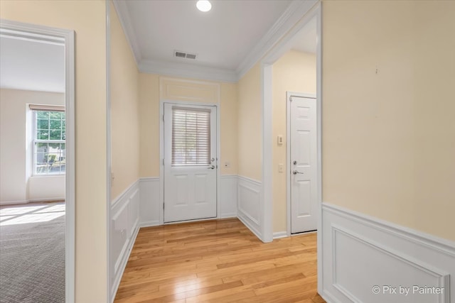 doorway featuring crown molding and light hardwood / wood-style floors