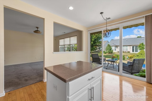 kitchen featuring white cabinets, light colored carpet, hanging light fixtures, and a notable chandelier